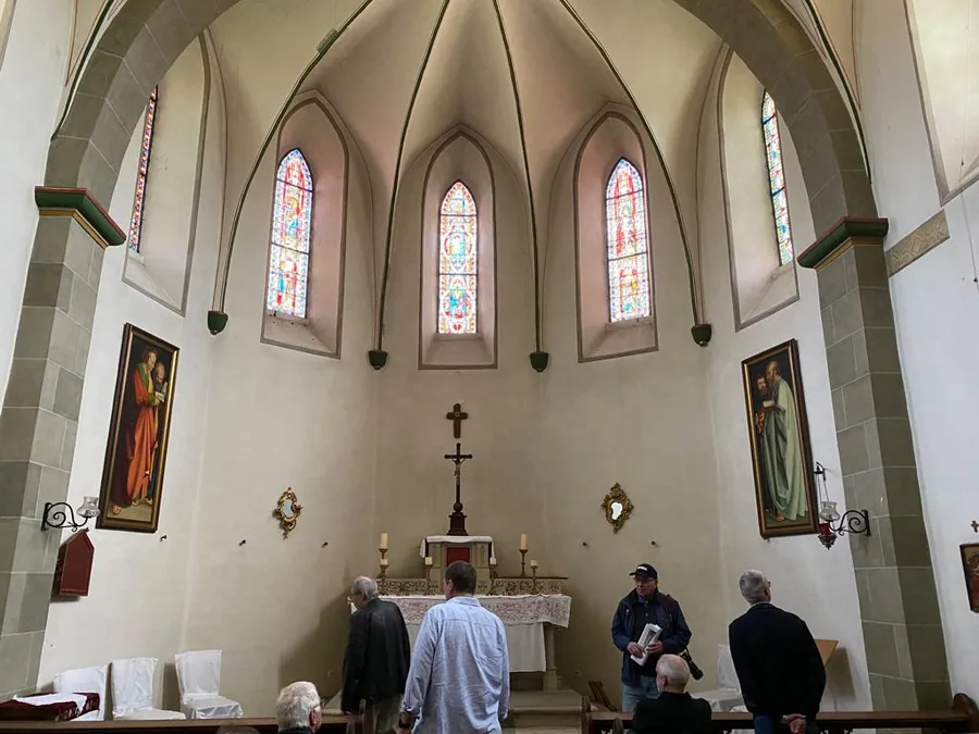 Blick in die Kapelle auf den Altar unter drei bunten Chorfenstern